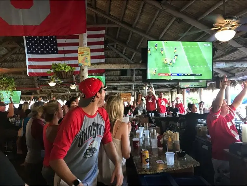 Fans on their feet under the chickee roof at Harold's Place as the game plays on the big screen