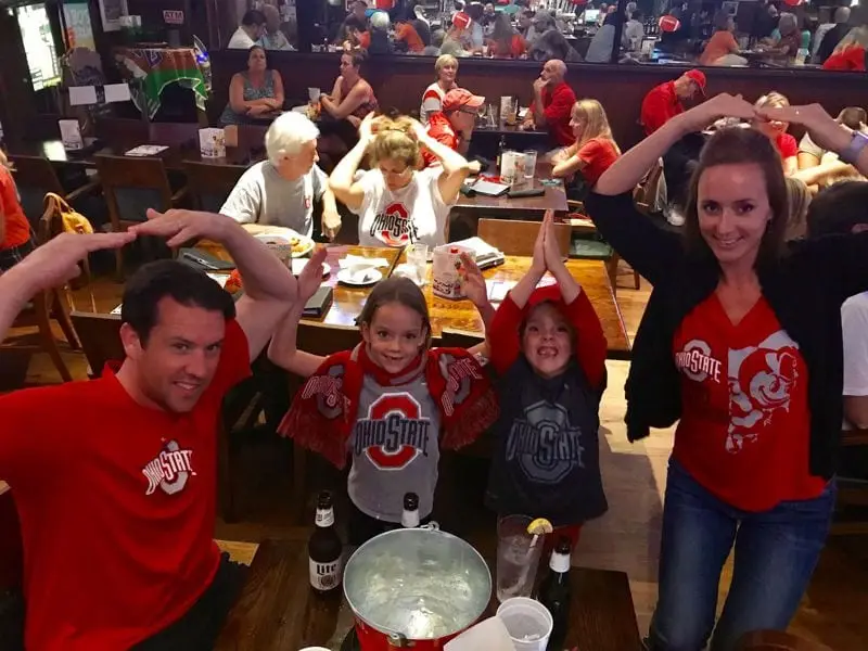 Families in scarlet cheering at a game watch table